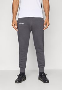 Sive trenerke iz mehkega blaga, z rebrastimi manšetami, z besedo "INTER" in Nike logotipom natisnjenim v beli barvi na levem stegnu.