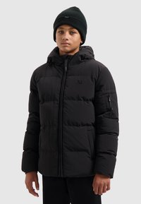 Zwarte pufferjack met capuchon, voorzien van een rits aan de voorkant, textuurstof en een klein logo op de borst. Draagt een bijpassende zwarte beanie.