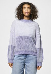 Ljubičasti džemper s prugama, visokog ovratnika, rebraste teksture, dugih rukava i opuštenog kroja, uparen sa svijetloplavim trapericama.