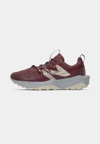 Scarpa da ginnastica bordeaux e beige con suola testurizzata, design geometrico della suola intermedia, parte superiore in rete e linguetta sul tallone, su sfondo semplice.
