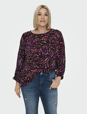 Schwarzes Oberteil mit lila und pinkem abstraktem Muster, lange Ärmel, runder Halsausschnitt, kombiniert mit zerrissenen blauen Jeans. Glatte Stofftextur.