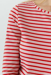 Langarmshirt met rode en roze strepen en een ronde hals, gemaakt van zachte stof, met gelijkmatig verdeelde horizontale strepen.