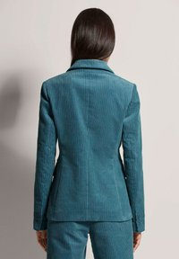 Teal corduroy blazer met verticale strepen, met notch-lapel en drie knopen op elke manchet. Getailleerde pasvorm en een zachte textuur.