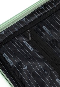 Interno della valigia di un delicato verde menta con rivestimento nero, caratterizzato da schemi stradali grafici, cerniere e sezioni etichettate. Le texture variano tra lisce e a rete.