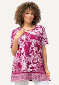 Kurzärmlige Tunika in Magenta mit weißen Blumen- und abstrakten Mustern. Sie hat einen Rundhalsausschnitt mit Kreuzdetail und einem strukturierten Saumakzent.