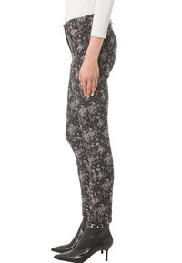 Czarno-białe spodnie w wzory o dopasowanym kroju, z kwiatowym nadrukiem. W połączeniu z czarnymi botkami na wysokim obcasie.
