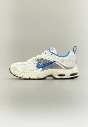 Chaussure de course Nike blanche et bleue avec tige en mesh, swoosh Nike bleu, semelle amortie et languette d’aide à l’enfilage sur fond neutre.