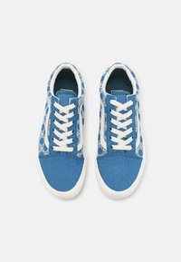 Blue canvas sneakers with white laces, featuring a patterned side. The toe and tongue are solid blue, with textured accents on the sides.