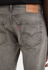 Gray denim jeans with a leather back patch, two rear pockets, and a red Levi's tab. The fabric has a slightly textured appearance.