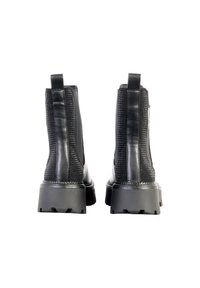 Botines de cuero negro hasta el tobillo con un respaldo texturizado, paneles laterales elásticos, suelas de goma gruesas y tiradores para facilitar su uso.