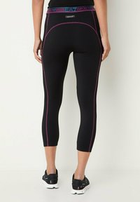 Leggings capri neri con dettagli di cucitura rosa e una vita elastica con logo brandizzato. Realizzati in tessuto elastico e testurizzato.