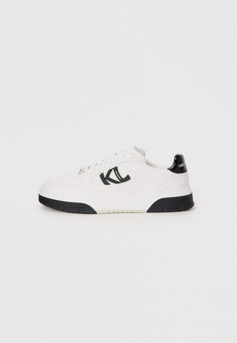 Hvit lær sneaker med svart gummisåle, med en fremtredende svart logo og teksturert detaljer på overdelen.