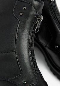 Black leather boots with a smooth texture, featuring a side zipper and metal accents, stitched detail, and a sturdy sole design.