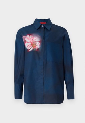 Chemise bleu marine avec un motif floral dans des tons de rose sur la poitrine gauche, dotée d'un col boutonné et d'une poche unique à l'avant.