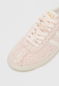 Sneaker rosa chiaro con un tessuto testurizzato, con accenti di perle sui lacci e una suola in gomma. Design semplice con un logo sulla linguetta.