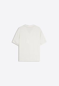 Chemise blanche unie à manches courtes, vue de dos, avec un col simple sur un fond clair.