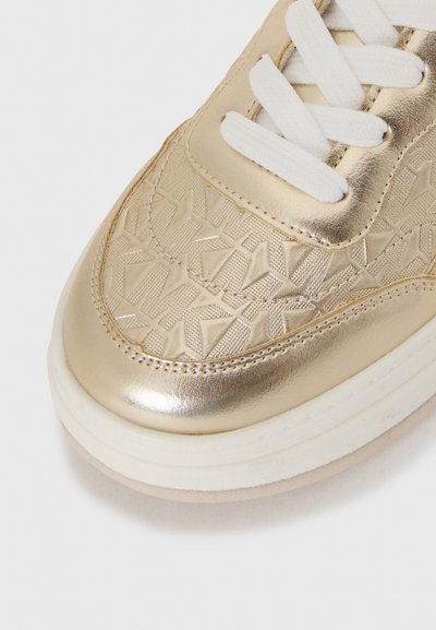 Gullmetalliske sneakers med teksturert overdel med geometriske mønstre, hvite lisser og en tykk kremfarget såle.