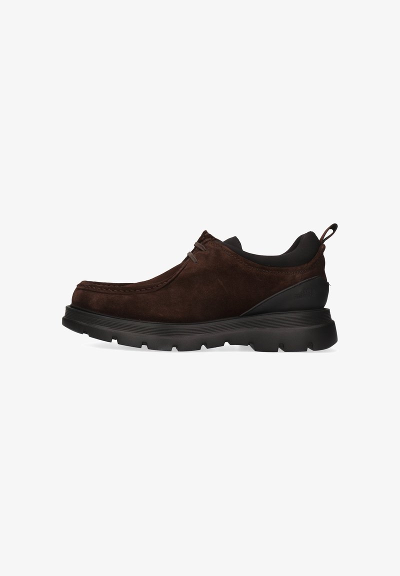 Bruine suède schoenen met een laag profiel, ronde neus en een contrasterende zwarte rubberen zool met een gestructureerde afwerking. Geen zichtbare veters.