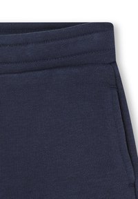 Pantaloni da tuta blu navy scuro realizzati in tessuto a coste, con una cintura elastica e tasche laterali con dettagli di cucitura discreti.