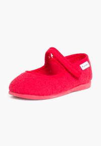 Zapatilla de terciopelo rojo con punta redondeada y una correa decorativa a lo largo del empeine. Presenta una parte superior de textura suave y suela plana de goma.