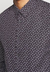 Donkergepatroneerde shirt met kleine, lichtblauwe geometrische vormen. Overhemd met knopen en een gespreide kraag met een subtiele textuur.