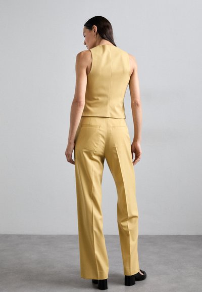 Top giallo su misura senza maniche e pantaloni a vita alta abbinati, realizzati in tessuto morbido, con un design aderente e gamba svasata.
