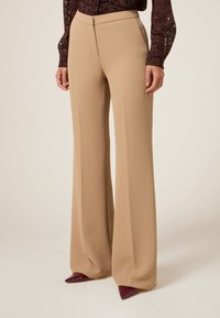 Beige wijde broek met een op maat gemaakte pasvorm, met een gladde textuur en een vloerlange snit, gecombineerd met puntige bordeauxrode schoenen.