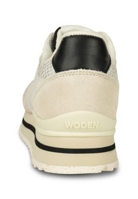 Vita och beige sneaker med en texturerad överdel i mocka och läder, svart hälaccent och en krämfärgad sula. Har WODEN-logotyp på hälen.
