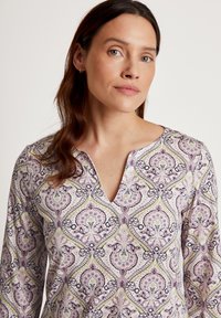 Langärmliges Oberteil in Lila und Creme mit einem Paisleymuster. Merkmale einen V-Ausschnitt und einen weichen, leichten Stoff.