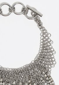 Collana in metallo con catena, caratterizzata da anelli d'argento interconnessi e file di pietre trasparenti sfaccettate in un design circolare. Texture liscia, finitura lucida.