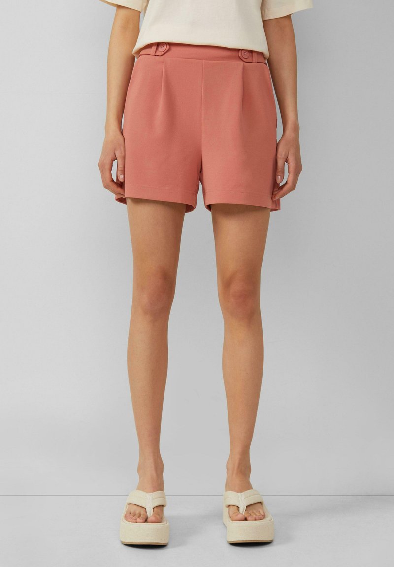 Shorts en rose poussiéreux, en tissu lisse, au style ajusté, avec deux plis avant et des accents de bouton à la taille.