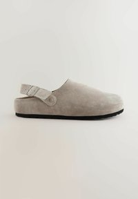 Sabot en suède gris avec une texture lisse, une bride arrière et une boucle réglable. Semelle en caoutchouc noir et design à orteil rond.