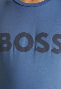 Blå bomullströja med rund halsringning och en framträdande svart "BOSS"-tryck framtill. Mjuk textur och figurnära design.