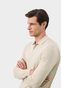Lichtbeige poloshirt met lange mouwen en een gekraagde hals, voorzien van een knoopsluiting, een gladde textuur en een aangesloten silhouet.