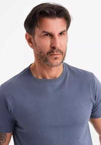 Šedé tričko s krátkým rukávem z měkkého materiálu, s kulatým výstřihem a přiléhavým střih, vhodné pro volný čas.