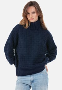 Pull tricoté bleu marine avec un col montant, doté d'un motif tissé texturé et de poignets et ourlet côtelés. Coupe décontractée et ample.