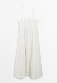 Robe en lin blanc avec des fines bretelles, longueur genou, présentant un design plissé et une fermeture éclair au dos. Tissu doux et texturé avec un ourlet effiloché.