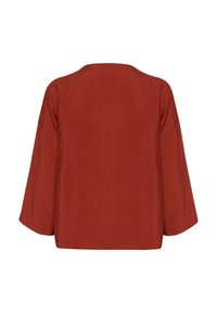 Rustfarvet top med en løs, kasseformet design, brede ærmer og en glat tekstur. Har en enkel rund hals og ingen yderligere detaljer.