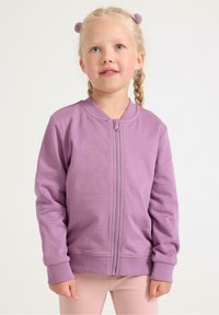 Lilla lynlåsjakke med rund halsudskæring og ribbede manchetter, lavet af blødt stof med en glat tekstur.
