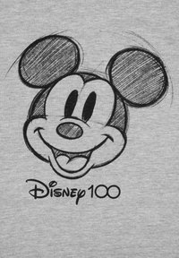 Maglietta grigia con una bozza nera di un topo cartone animato sorridente con grandi orecchie, accompagnata dalla scritta "Disney 100" in un font giocoso.