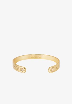 Le bracelet jonc plaqué or présente un design en étoile et lune croissante avec des accents de pierres précieuses claires, une finition lisse et des extrémités ouvertes.