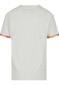 Camiseta blanca hecha de algodón con textura moteada. Las mangas cortas presentan acentos de patrón multicolor en los puños.