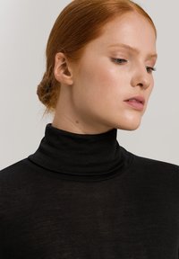 Maglione nero a collo alto realizzato in un tessuto morbido e leggero. Presenta un colletto aderente e una consistenza liscia, con una silhouette aderente.