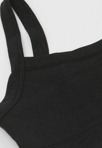 Černý bavlněný top bez rukávů s tenkými ramínky, který má hladkou texturu a jednoduchý design. Okraje mají začištěný lem.