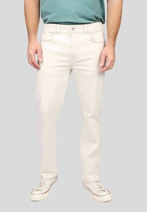 Jean beige clair avec une coupe droite, cinq poches et une fermeture à bouton. Associe des baskets blanches avec des accents rouges. Texture de tissu lisse.