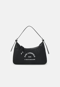 Sac à main en nylon noir avec une silhouette incurvée, quincaillerie argentée et une seule bandoulière. Comprend du texte imprimé blanc et une fermeture éclair.