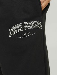 Fekete pamut jogger nadrág, puha textúrával. A bal lábon fehér logó felirat található: "JACK & JONES" és az alapítás éve.