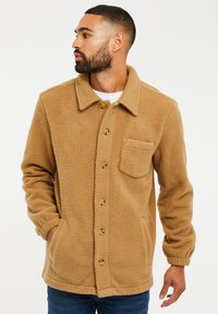 Chaqueta de forro polar marrón con cierres de botones, cuello y un bolsillo frontal. Presenta una tela texturizada y puños elásticos.