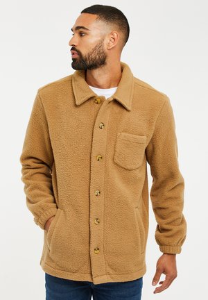 Chaqueta de forro polar marrón con cierres de botones, cuello y un bolsillo frontal. Presenta una tela texturizada y puños elásticos.