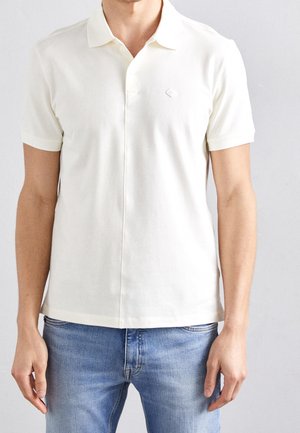 Polo shirt in zachte, crèmekleurige katoen met een kraag, korte mouwen en een subtiele logo-accessoire. Aangesloten pasvorm met een rechte zoom en minimale naden.